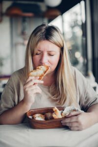 Charming blond plus size woman smelling the piece of fresh toasted bread in restaurant Enjoying food